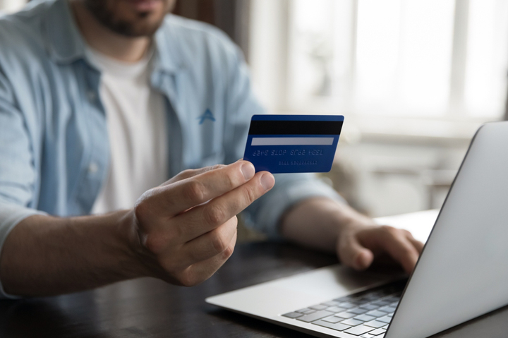 closeup of male hand holding credit card, typing on laptop