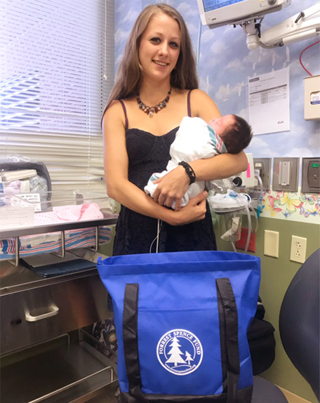 Melissa Nanney holding baby with tote bag in front