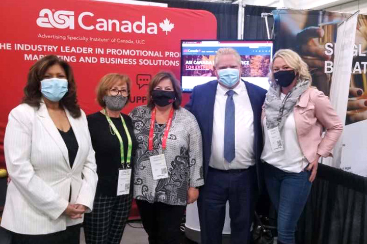 group of women and one man standing in front of ASI Canada banner