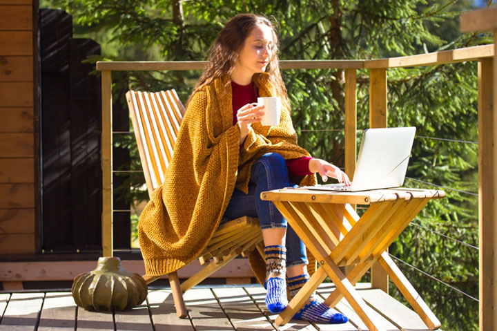 woman working outside wrapped in blanket drinking from mug