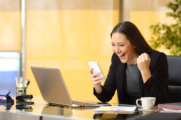 female at desk looking at phone, excited