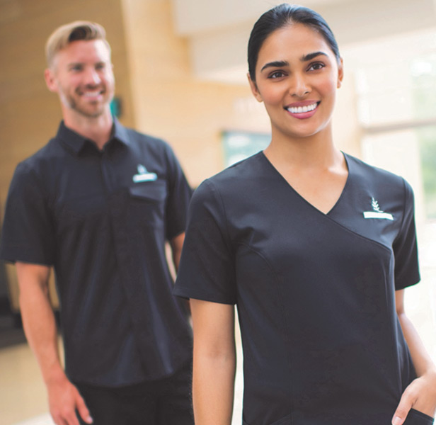 man and woman wearing dark scrubs and smiling