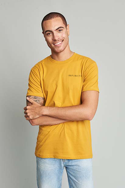 man wearing gold t-shirt, arms folded