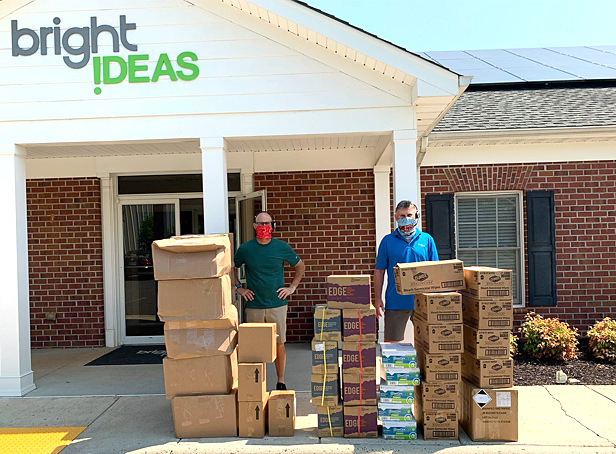 two men standing outside of Bright Ideas next to delivery boxes