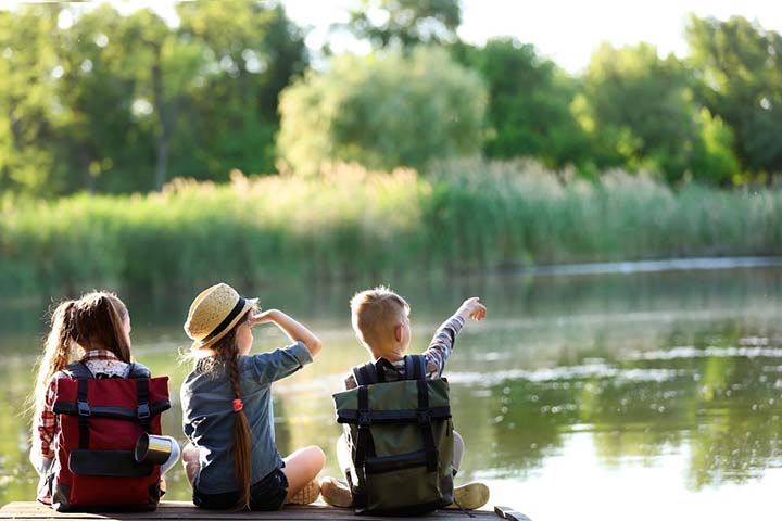 Young children sitting around a lake