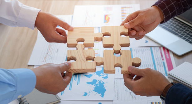 four hands pushing puzzle pieces together