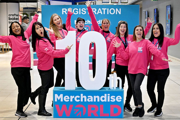 women from Sourcing City standing in front of Merchandise World tradeshow sign