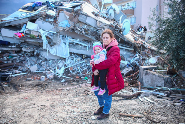 Turkish woman holding child amid earthquake rubble