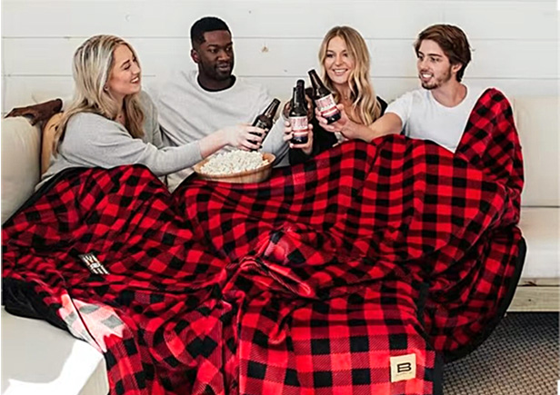 people sitting under black & red check blanket having drinks