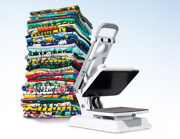 heat press next to a stack of decorated t-shirts