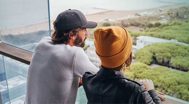 man and woman standing on balcony looking out over grassy area