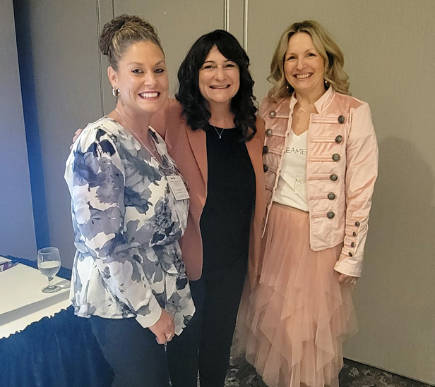 three women standing, smiling