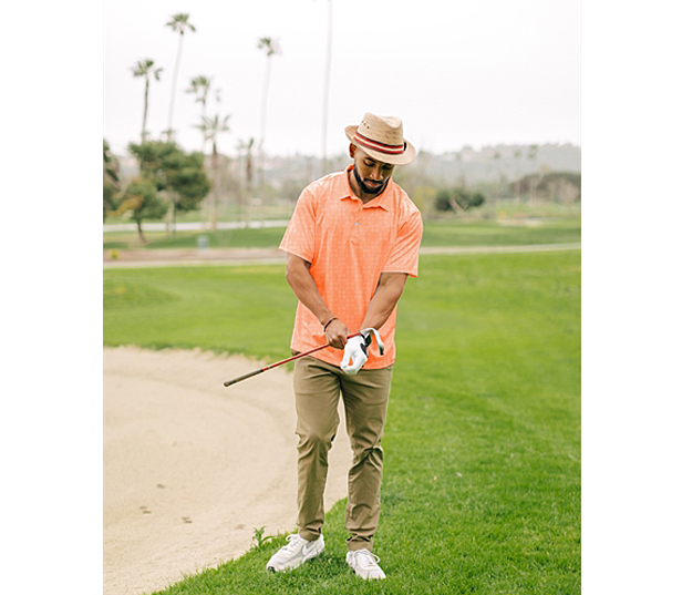 man on golf course wearing orange polo shirt