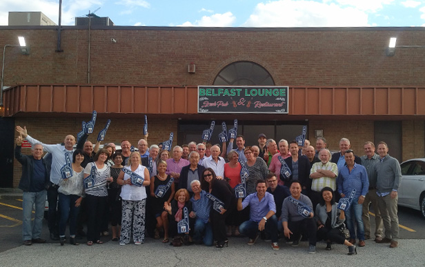 large group of people standing outside a bar