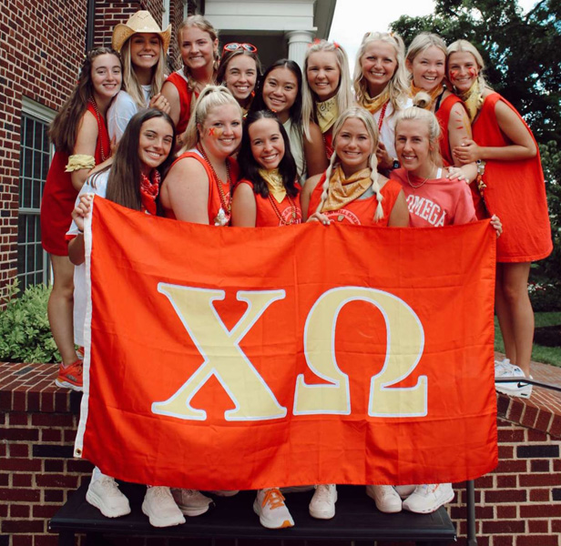 sorority girls holding up Chi Omega flag