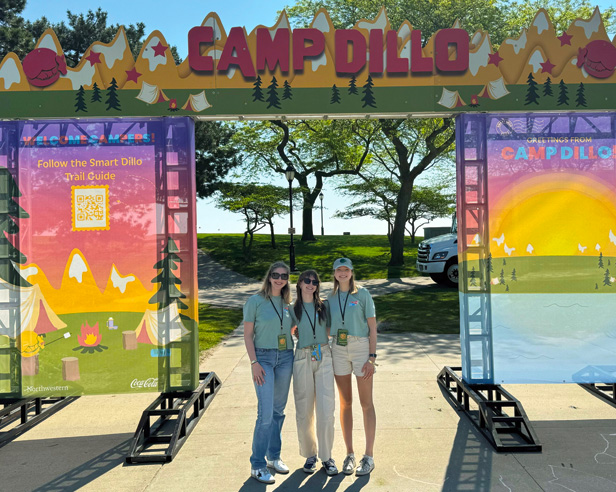 three college female students standing in front of music festival sign